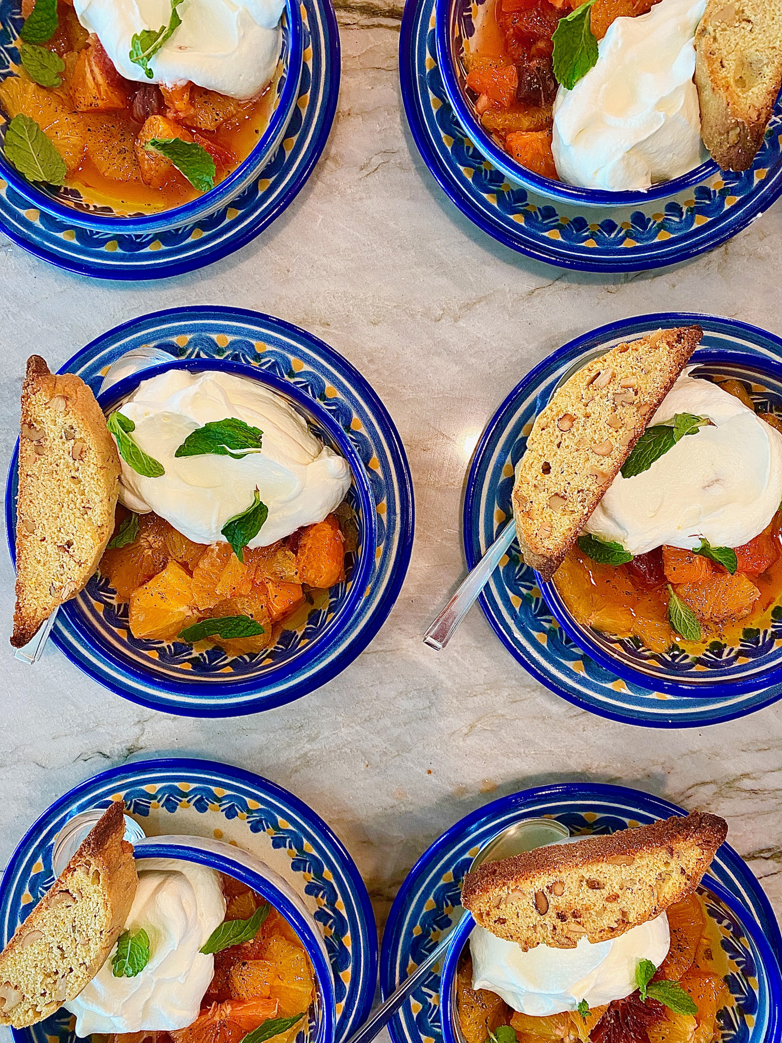 Bright blue plates with fresh fruit, cream, mint and crispy biscotti