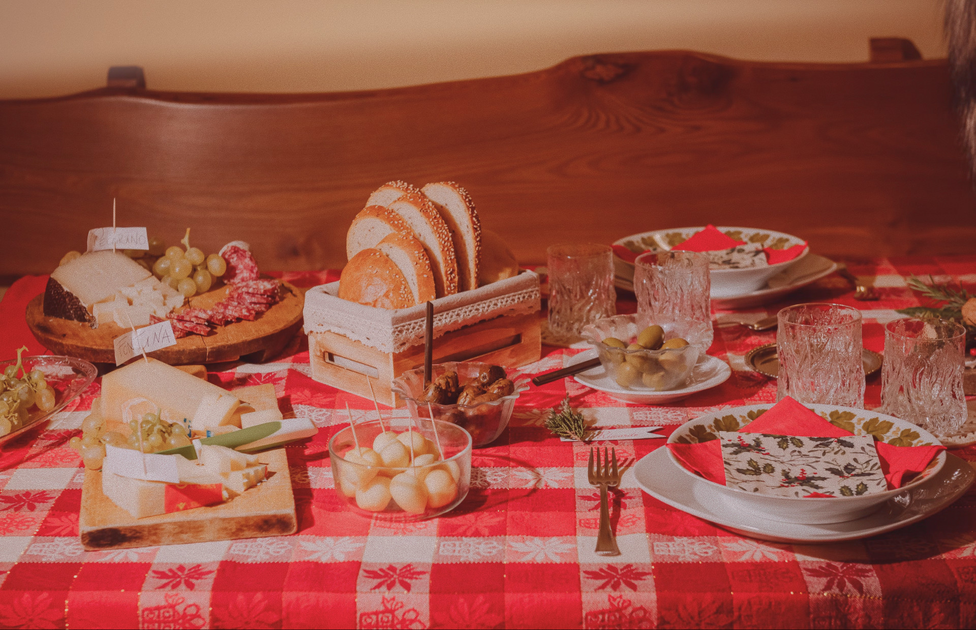 A table set for a dinner with charcuterie, on a bright red checkered tablecloth